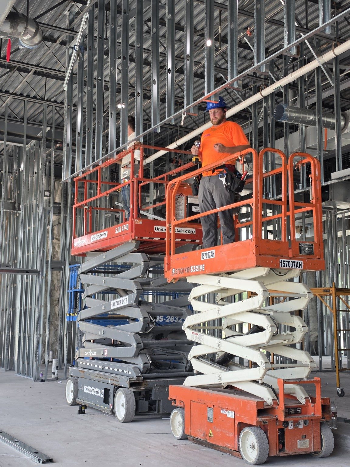Right Hand Construction crew member framing a commercial build-out from a scissor lift